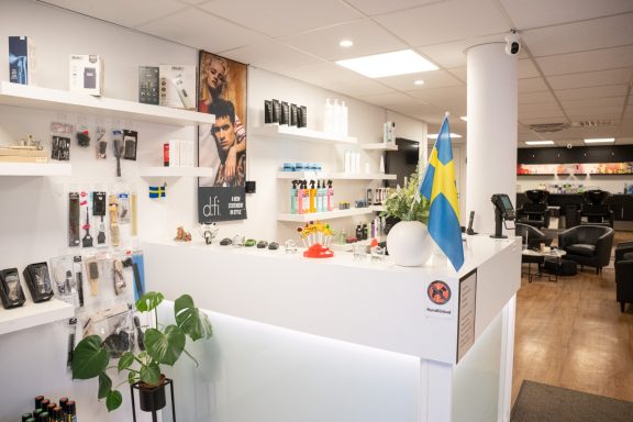 Receptionsdisk med produkter, växt och svensk flagga i en modern kontorsmiljö.